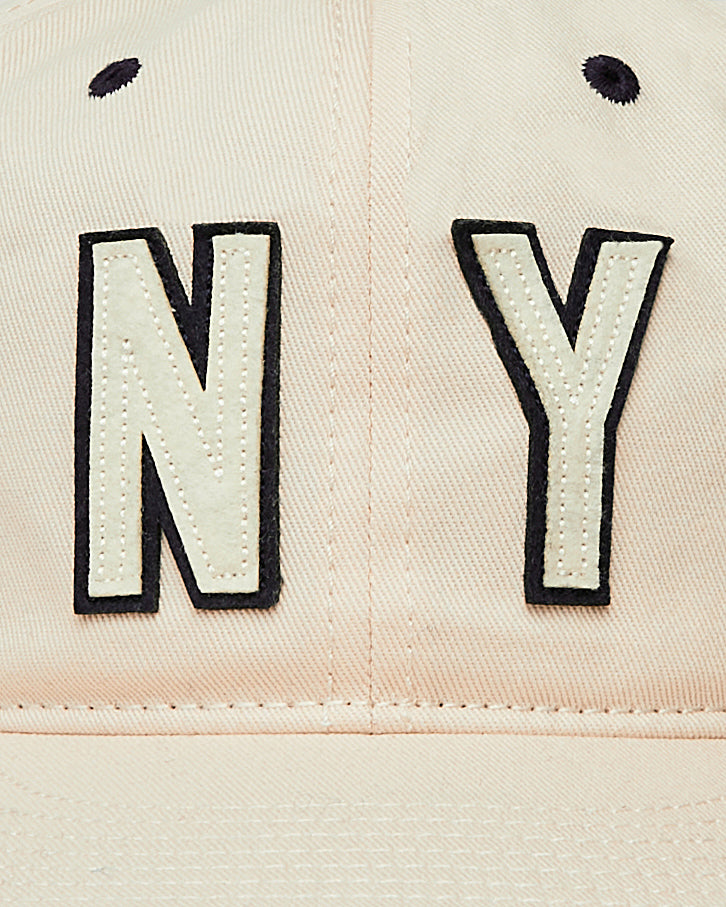 Close-up of the Ebbets Field New York 1939 World's Fair Cotton Twill Ballcap in beige, featuring large white NY letters with black outlines embroidered on the front and two small black stitched eyelets above.