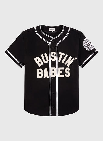 The Ebbets Field Babe Ruth Bustin’ Babes Authentic Wool Baseball Jersey features black wool, white buttons and trim, bold “BUSTIN’ BABES” text on the front, plus a Sand Knit Athletic patch on the left sleeve.
