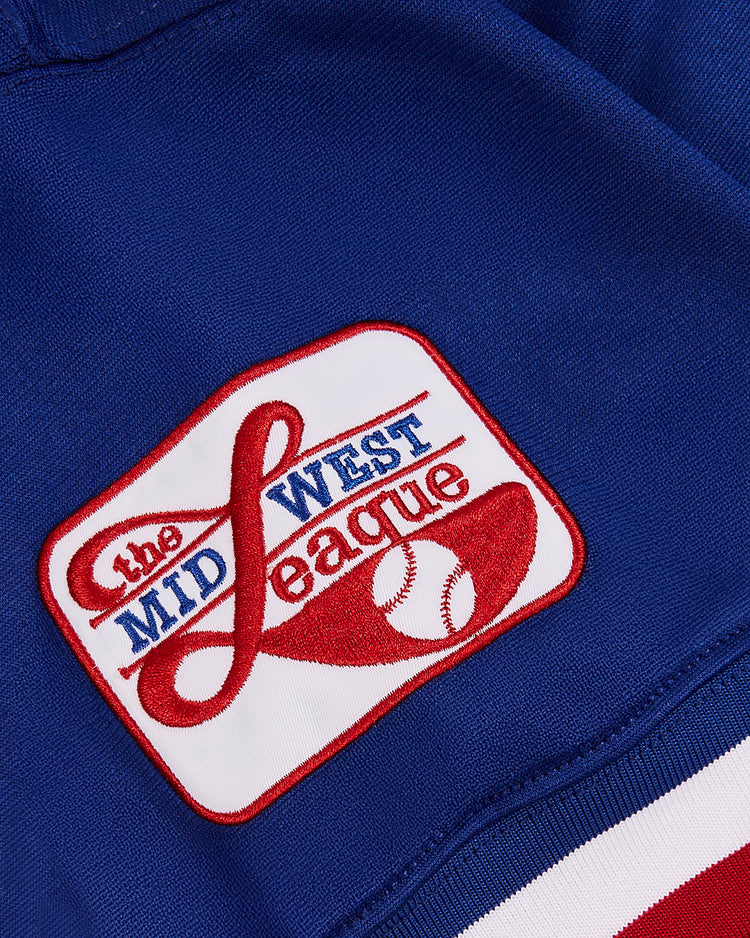 A close-up of the Greg Maddux Peoria Chiefs V-Neck Jersey by Ebbets Field shows a Midwest League patch with red and blue text, a red baseball graphic, and classic red and white stripes honoring minor league heritage.