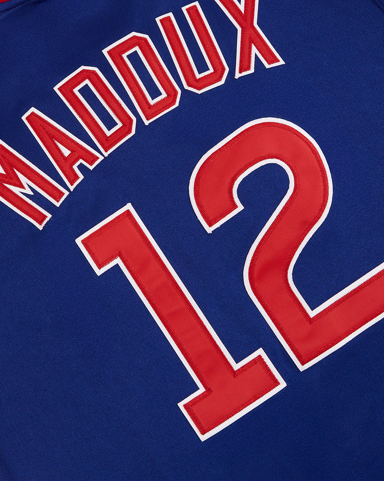 The Ebbets Field Greg Maddux Peoria Chiefs V-Neck Jersey features bold red MADDUX and number 12 outlined in white on blue, echoing the classic minor league style.