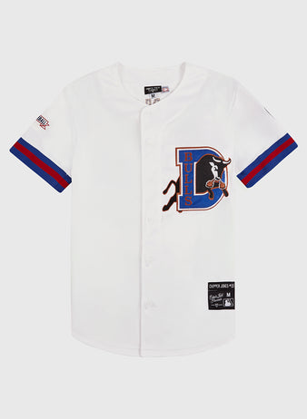 The Chipper Jones Durham Bulls Button Up Jersey by Ebbets Field is a white jersey with blue and red-striped sleeves, a large bull logo on the left chest, and several patches—ideal for Atlanta Braves memorabilia collectors.