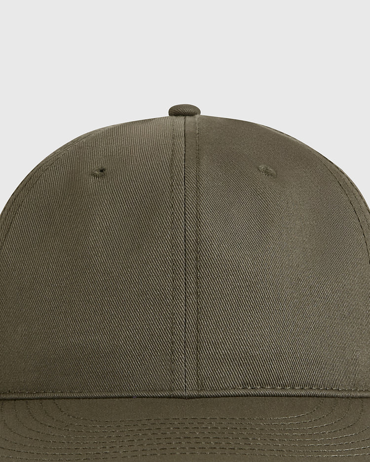 Close-up of the Ebbets Field Olive Green Cotton Twill Ballcap, featuring visible stitching and side ventilation holes, set against a plain gray background.