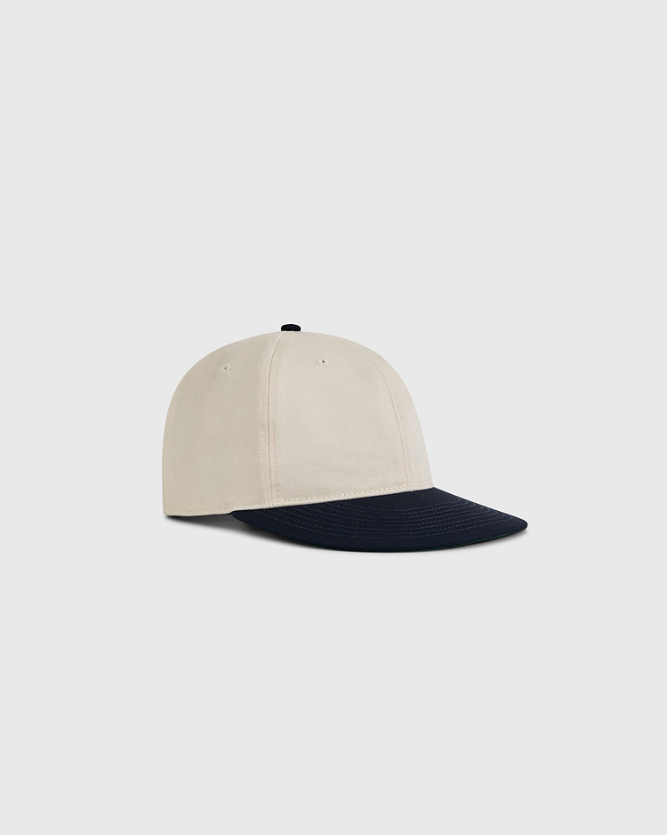 The Ebbets Field Natural and Navy Cotton Twill Ballcap features a cream crown and black curved brim, made from cotton twill, shown on a plain light gray background.