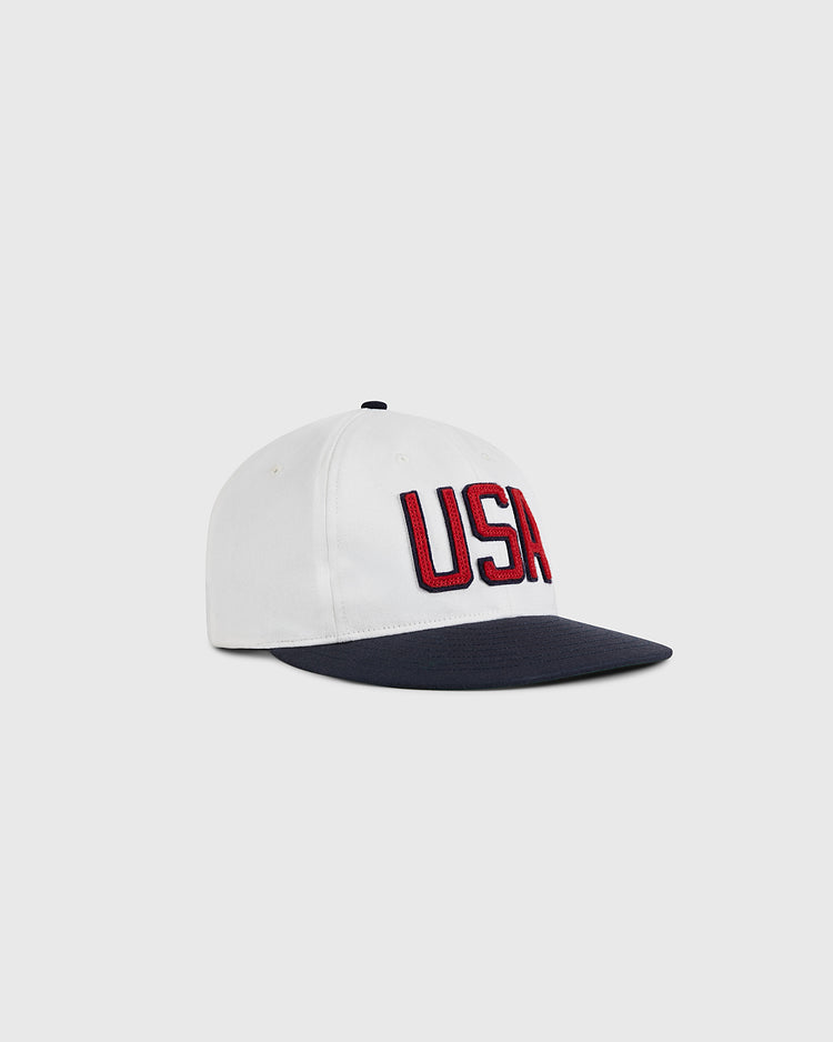 The Ebbets Field USA National Team Cotton Twill Ballcap is a white hat with a navy brim and large red and black embroidered 
