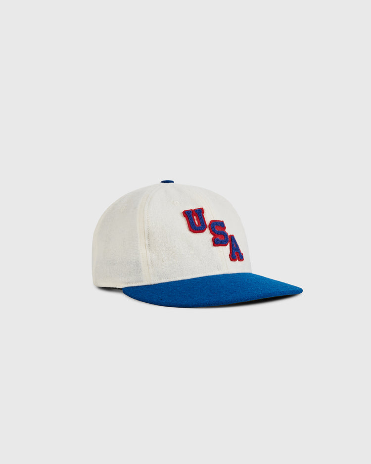 The Ebbets Field USA Miracle On Ice 1960 Wool Ballcap is a white cap with a blue brim, featuring red and blue embroidered 