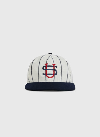 The Ebbets Field US Tour Of Japan 1934 Authentic Wool Ballcap features white wool with thin navy stripes, a navy brim, and an overlapping red and navy U-S logo embroidered on the front, inspired by the historic 1934 tour.
