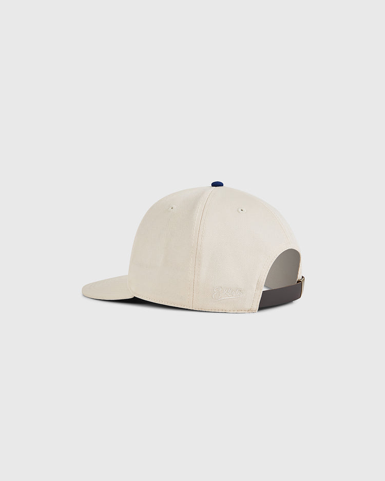 The Ebbets Field Santurce Cangrejeros 1939 Cotton Twill Ballcap in beige features a curved brim, navy blue top button, adjustable strap at the back, and a small embroidered logo above the opening for vintage baseball style.