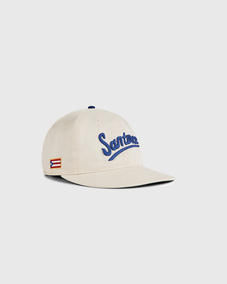 The Ebbets Field Santurce Cangrejeros 1939 Cotton Twill Ballcap features beige cotton twill, blue “Santurce” embroidery on the front, a Puerto Rican flag patch on the side, and is shown against a light gray background.