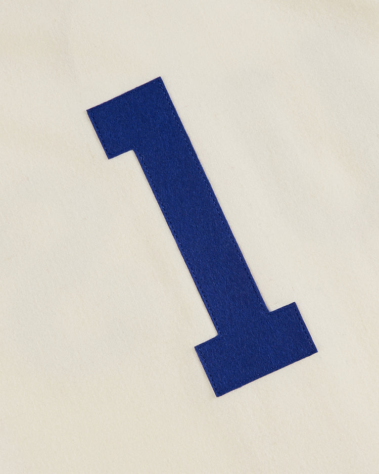 A bold blue number one stands out on an off-white background, echoing the vintage look of the 1936 USA National Team Authentic Wool Baseball Jersey by Ebbets Field.