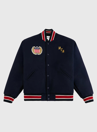 The Ebbets Field USA 1960 Miracle On Ice All-Wool Varsity Jacket features a navy body with red, white, and black striped cuffs and collar, a USA crest patch on the left chest, and gold 