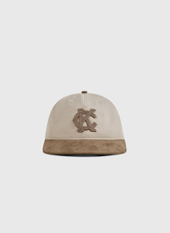 The Ebbets Field Kansas City Monarchs 1945 Cotton Twill Suede Ballcap features a beige crown, brown suede brim, and embroidered overlapping KC logo, shown against a plain white background.