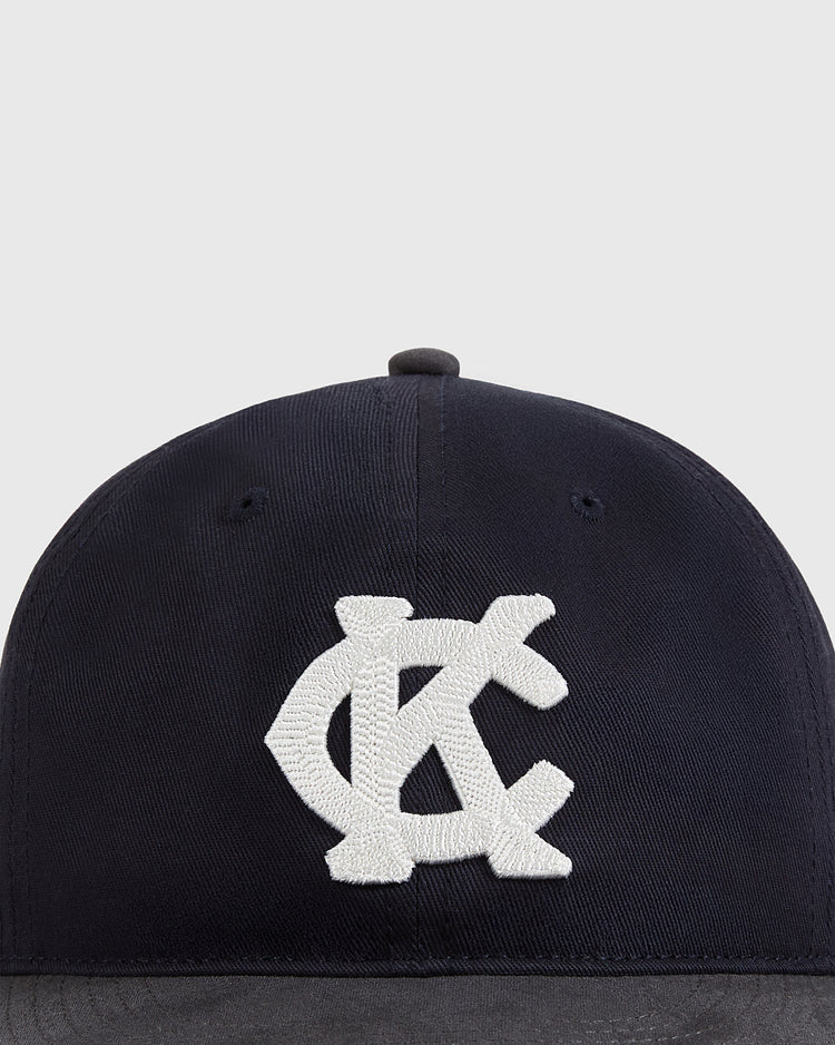 The Ebbets Field Kansas City Monarchs 1945 Cotton Twill Suede Ballcap is black with a large white interlocking KC logo embroidered on the front, set against a plain light gray background.