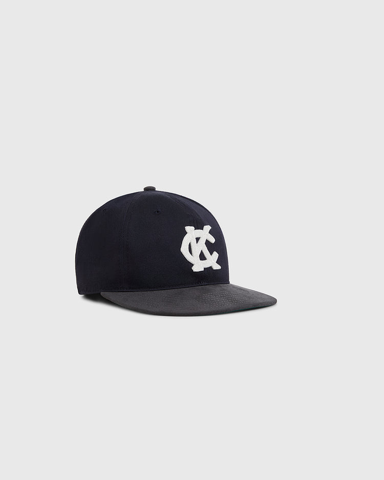 The Ebbets Field Kansas City Monarchs 1945 Cotton Twill Suede Ballcap features a navy crown, flat black brim, and a white embroidered NY logo, inspired by classic Negro Leagues style, shown on a plain light gray background.