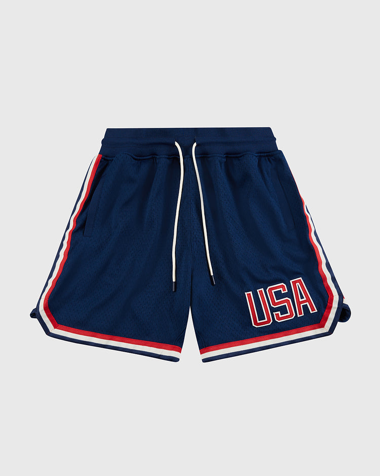 The Ebbets Field USA National Team Mesh Shorts feature navy blue breathable knit mesh, red, white, and blue striped trim, white drawstrings, and bold red and white “USA” lettering on the left leg, displayed on a plain light background.