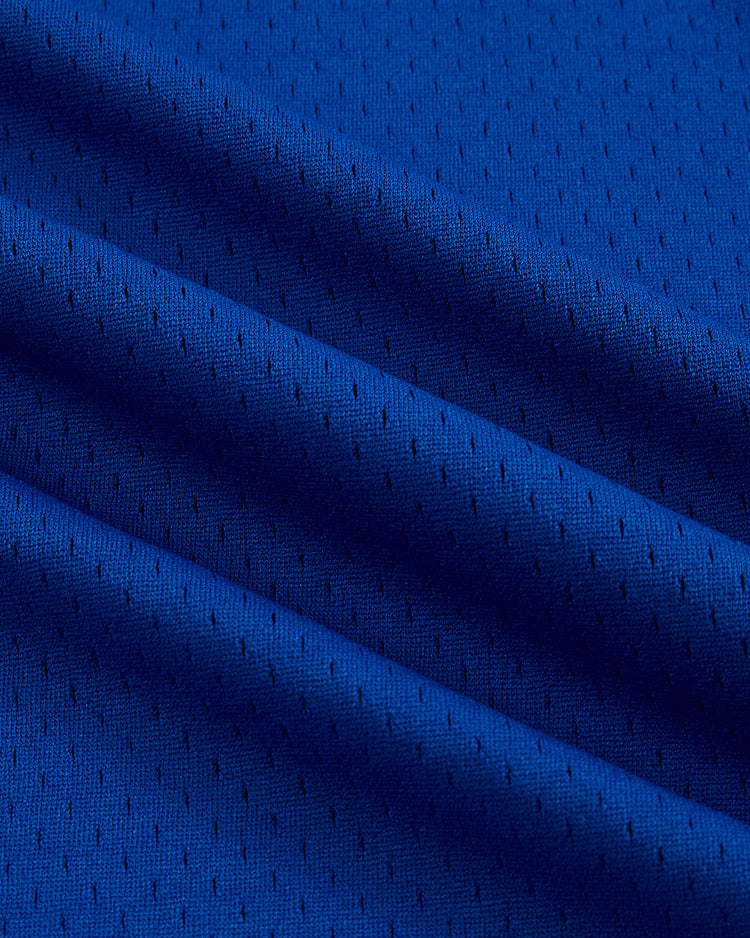 Close-up of vibrant blue mesh fabric with small, even perforations and soft folds, showcasing the texture and detail of the Santurce Cangrejeros Mesh V-Neck Jersey by Ebbets Field.