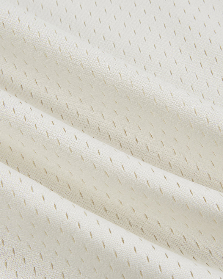 Close-up of the Ebbets Field Satchel Paige All-Stars Mesh V-Neck Jersey's off-white mesh fabric, featuring small perforations and soft folds that evoke the classic look of vintage Negro League baseball uniforms.