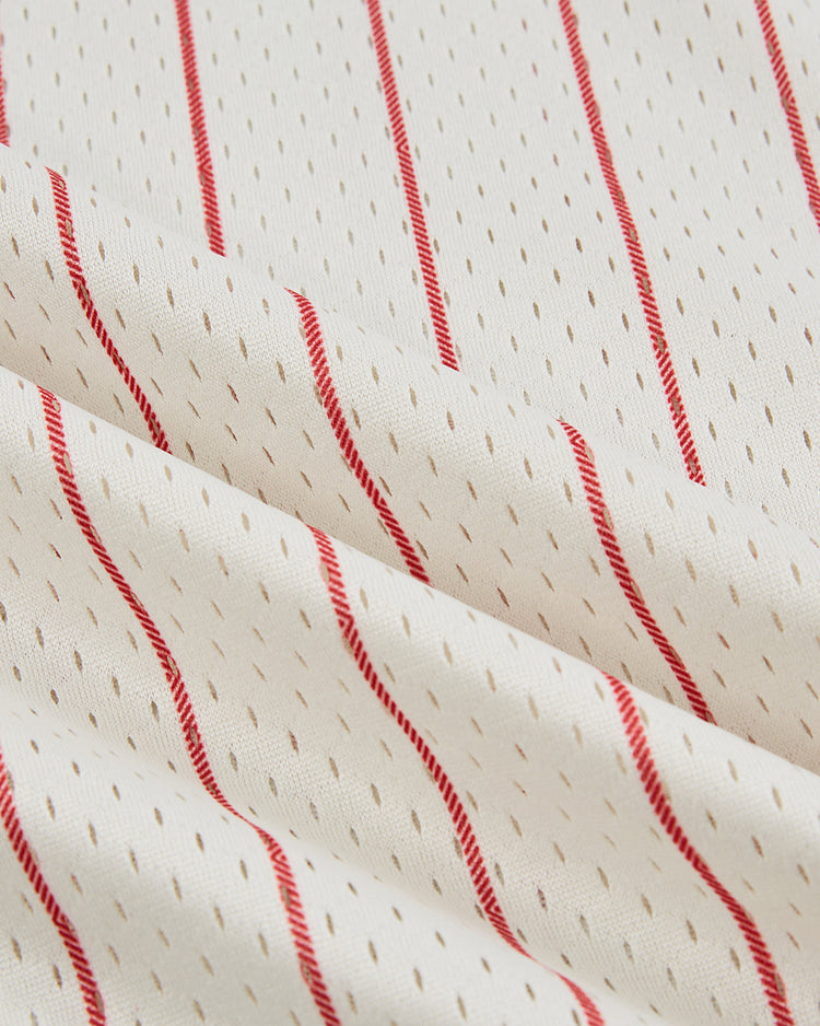 A detailed view of the Ebbets Field Havana Cubans Mesh V-Neck Jersey shows white mesh with beige dashes and diagonal red stripes, capturing the textured look and vintage feel inspired by the legendary baseball team.