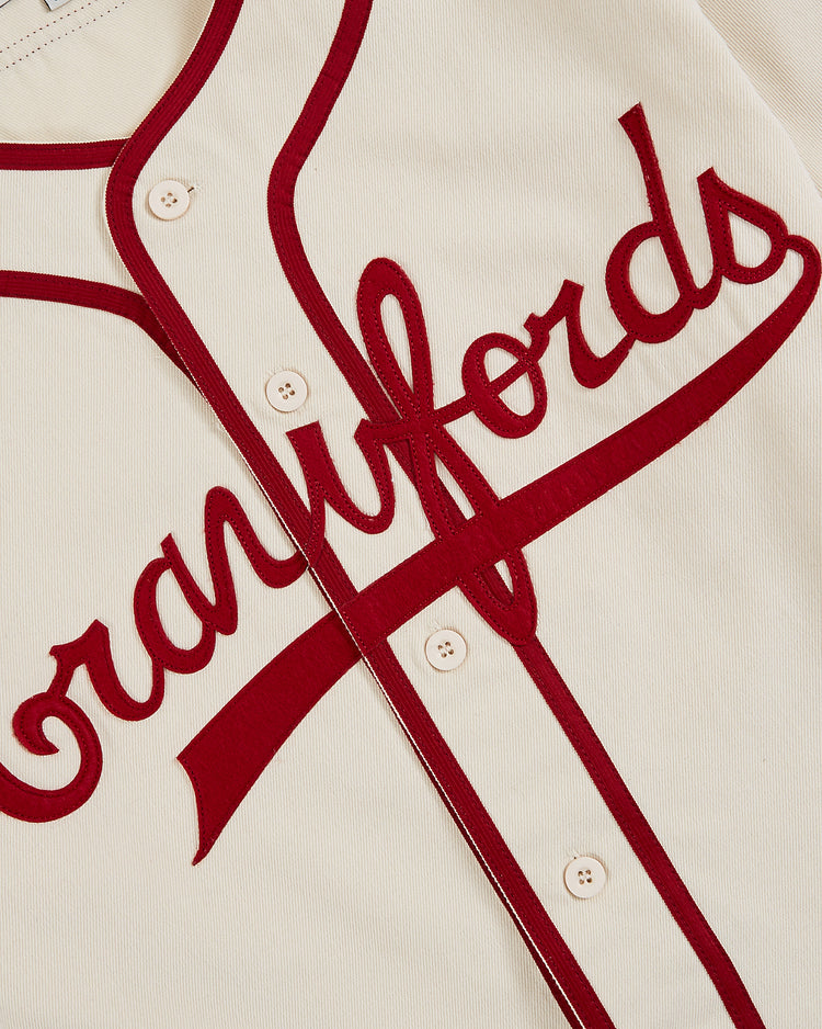 A close-up of the Ebbets Field Pittsburgh Crawfords 1933 Cotton Twill Jersey shows cream fabric, red piping, red 
