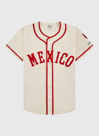 The Ebbets Field Diablos Rojos del Mexico Cotton Twill Baseball Jersey features a cream color, red trim and buttons, bold red “MEXICO” lettering, a left sleeve patch, and celebrates Diablos Rojos de México heritage.
