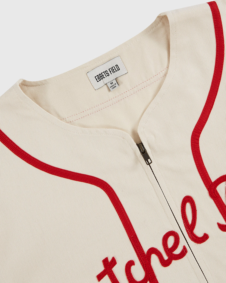 A close-up of the Ebbets Field Satchel Paige All-Stars 1933 Cotton Twill Jersey, cream-colored with red piping and cursive lettering. The inside collar tag reads 
