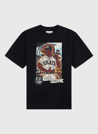 The Karabo Poppy x Ebbets Field Josh Gibson Short Sleeve Graphic Tee by Ebbets Field features a vibrant baseball player graphic and honors the Negro Leagues, with “Josh Gibson” and “EF X KROST” text over a field-inspired background.