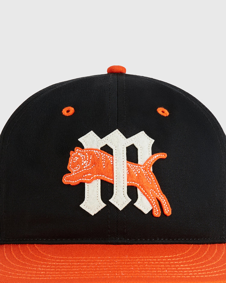 The Ebbets Field Marianao Tigres Cotton Twill Ballcap features a black crown, orange brim and top button, a white Gothic “M,” and an orange embroidered leaping tiger—a classic Cuban League design.