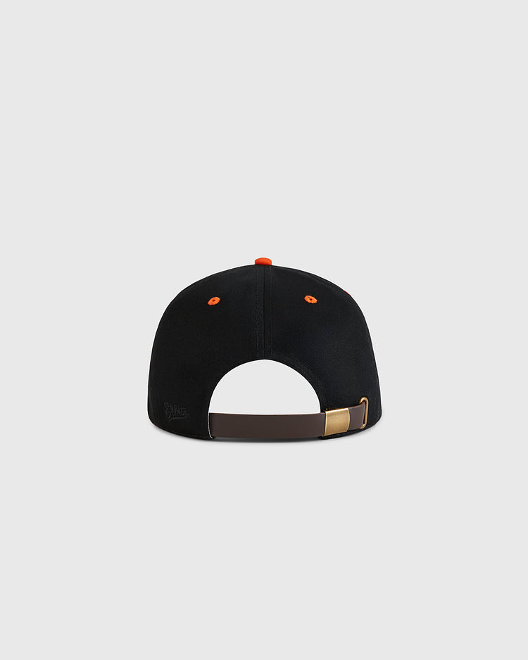 The Ebbets Field Marianao Tigres Cotton Twill Ballcap, shown from the back, features a black design with an adjustable brown strap, gold buckle, and orange accents on the top button and ventilation holes against a light gray background.