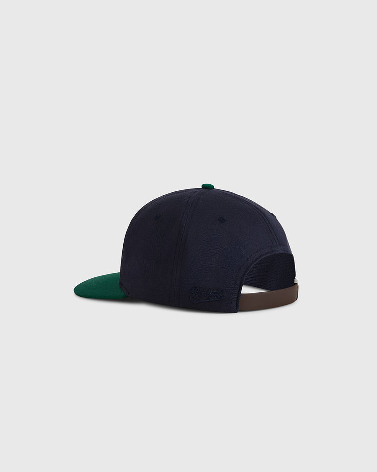 The Ebbets Field University of Notre Dame Shamrock Cotton Twill Ballcap features navy blue cotton twill, a green brim, adjustable brown strap, and a small embroidered logo at the back for classic vintage style.