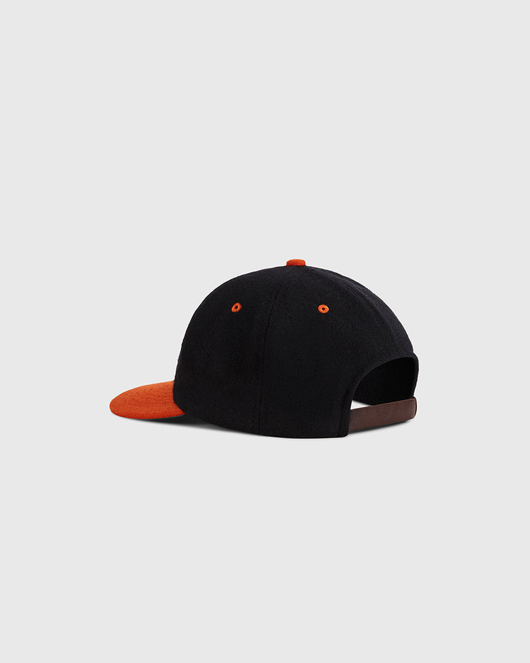 The Aguilas Cibaenes 1955 Authentic Wool Ballcap by Ebbets Field features a black crown, orange brim, button accents, and an adjustable strap. Shown from the back against a light gray background, it pays tribute to Dominican winter league history.