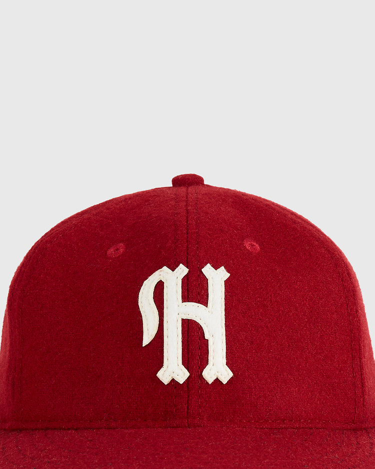 A close-up of the Ebbets Field Habana Leones Cuba 1940 Authentic Wool Ballcap, a red cap with a white gothic 