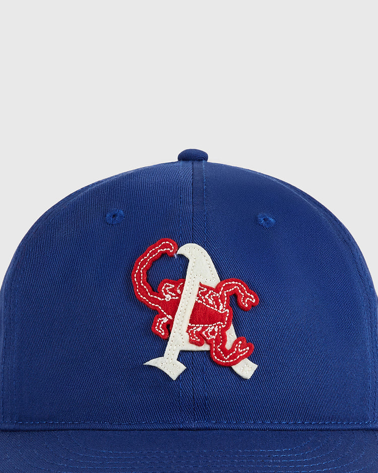The Ebbets Field Almendares Alacranes Cotton Twill Ballcap is royal blue with a red embroidered scorpion wrapped around a large white 