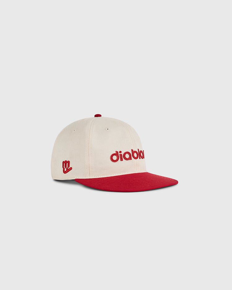 The Ebbets Field Diablos Rojos del Mexico Cotton Twill Ballcap features a cream crown, red brim, “diabla” embroidered in red on the front, and a small red side symbol. Shown against a plain light background.