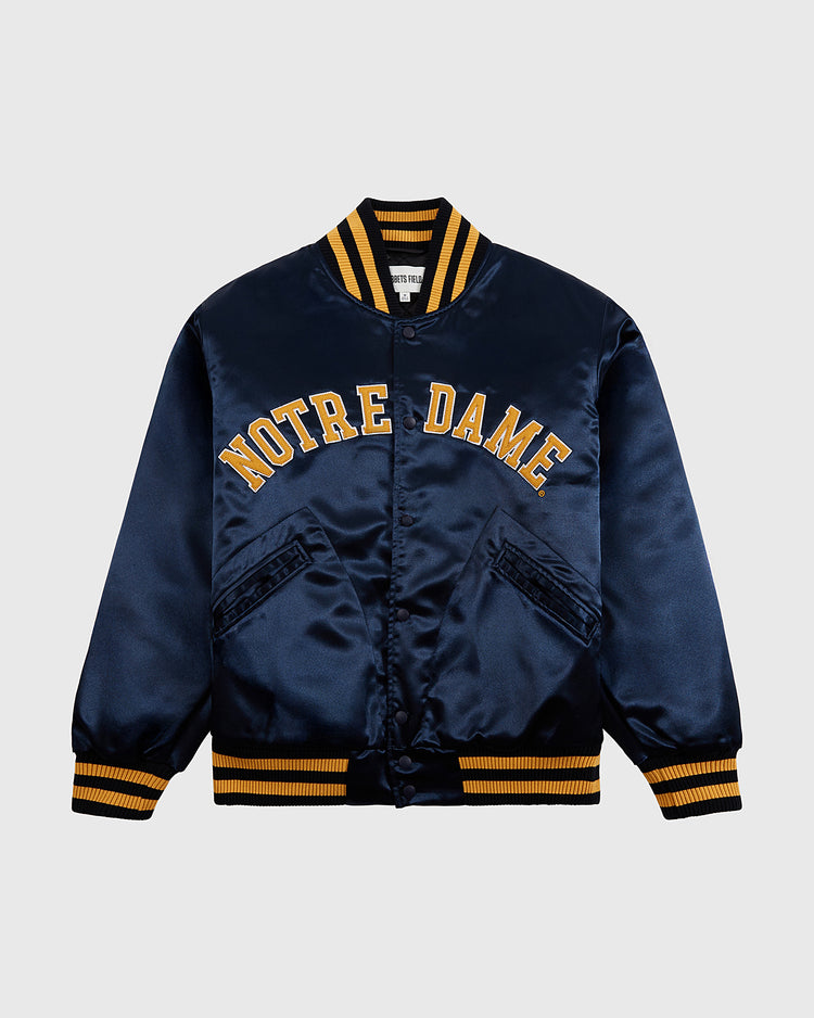 The Ebbets Field Notre Dame Satin Varsity Jacket features navy blue satin, bold yellow NOTRE DAME lettering, yellow and navy striped trim, and two diagonal front pockets for classic Fighting Irish style.
