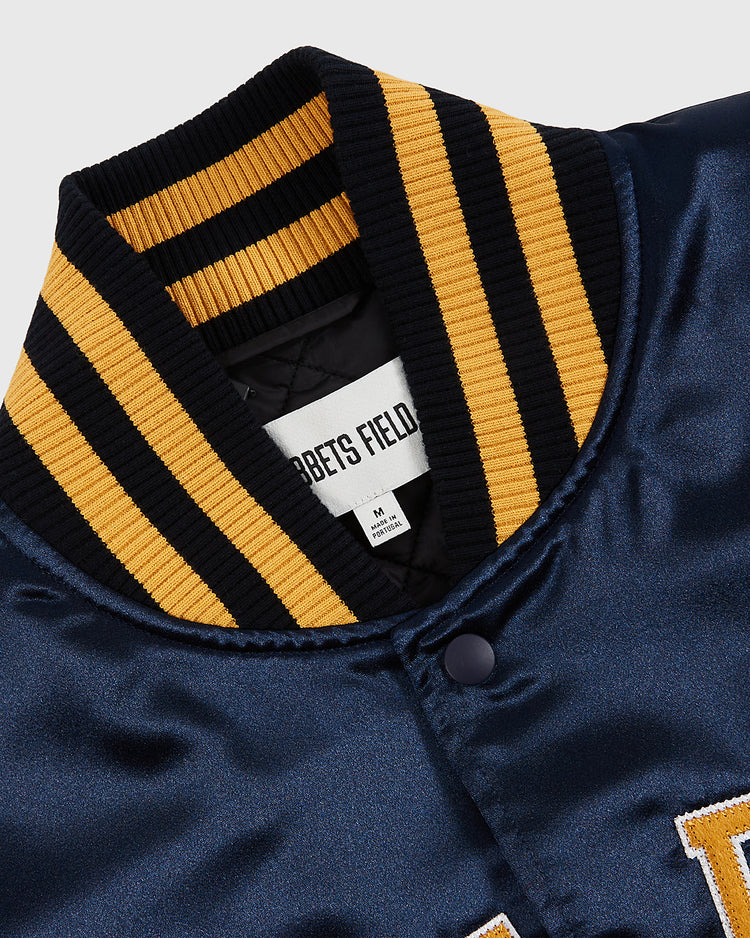 Close-up of the Notre Dame Satin Varsity Jacket by Ebbets Field, in navy blue satin with a black and yellow striped ribbed collar and a white inside label showing size M, inspired by classic varsity style.