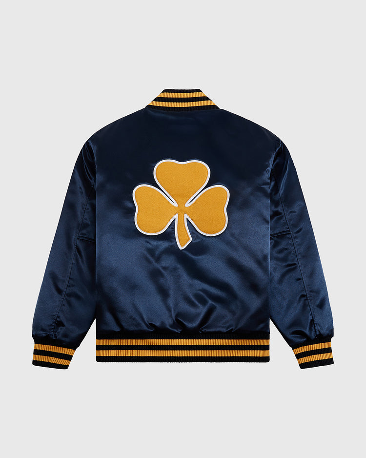 The Ebbets Field Notre Dame Satin Varsity Jacket features navy blue satin, yellow ribbed cuffs, collar and hem, and a bold yellow clover graphic on the back for a vintage-inspired look.