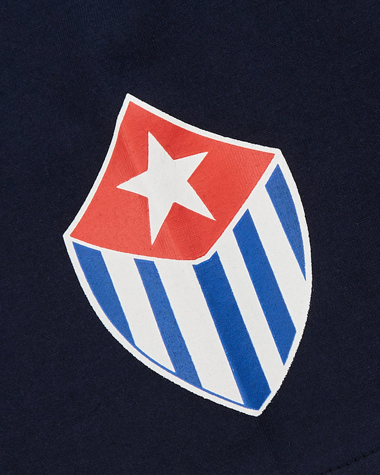 The Almendares Alacranes Short Sleeve Graphic Tee by Ebbets Field features a Cuban baseball-inspired shield logo with a red, white-starred top and blue-and-white striped bottom, evoking vintage Havana shirts on a dark blue background.