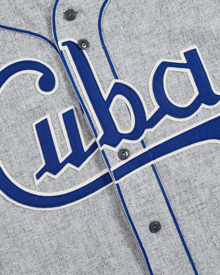 Close-up of the EFF Cuba National Team 1947 Authentic Wool Road Baseball Jersey: gray wool with blue trim, white outline, bold blue “Cuba” script on the front, echoing the iconic 1947 style. Black buttons run along the center.