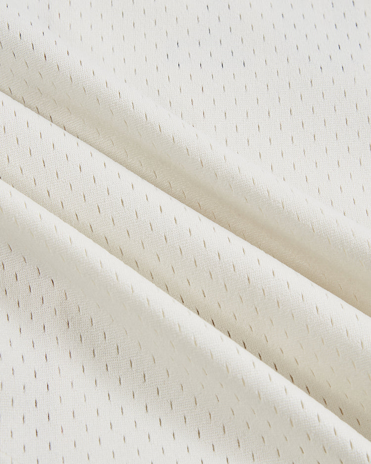 Close-up of the Ebbets Field Havana Cubans Mesh Button-Up Jersey, featuring cream-colored fabric with small, evenly spaced perforations and diagonal folds, evoking a soft vintage texture inspired by minor league baseball classics.