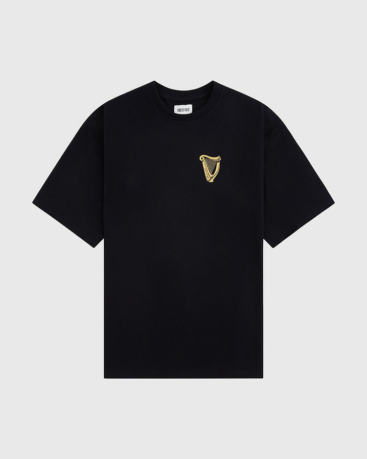 The Guinness Tortoise Short Sleeve Graphic Tee by Ebbets Field features a small gold harp emblem on the left chest, displayed on a light gray background.