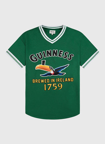 The Ebbets Field Guinness Toucan Mesh V-Neck Jersey is a green short-sleeve top with white trim, featuring a large Guinness logo, colorful toucan with pint, and “Brewed in Ireland 1759” text on the front.