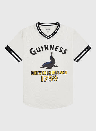 The Ebbets Field Guinness Seal Mesh V-Neck Jersey features white short sleeves with black accents, the word GUINNESS, a seal balancing a bottle, and 