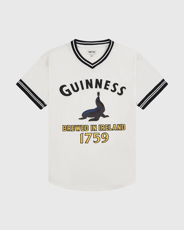 The Ebbets Field Guinness Seal Mesh V-Neck Jersey features white short sleeves with black accents, the word GUINNESS, a seal balancing a bottle, and 