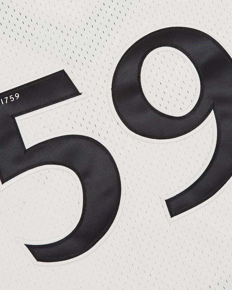 Close-up of the Ebbets Field Guinness Seal Mesh V-Neck Jersey, showing its white mesh fabric with large black 