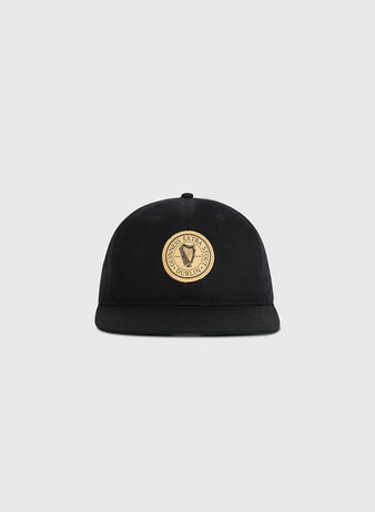 The Ebbets Field Guinness Extra Stout Badge Cotton Twill Ballcap features a black design with a round beige patch reading Dublin Excise on the front, displayed against a plain light gray background.