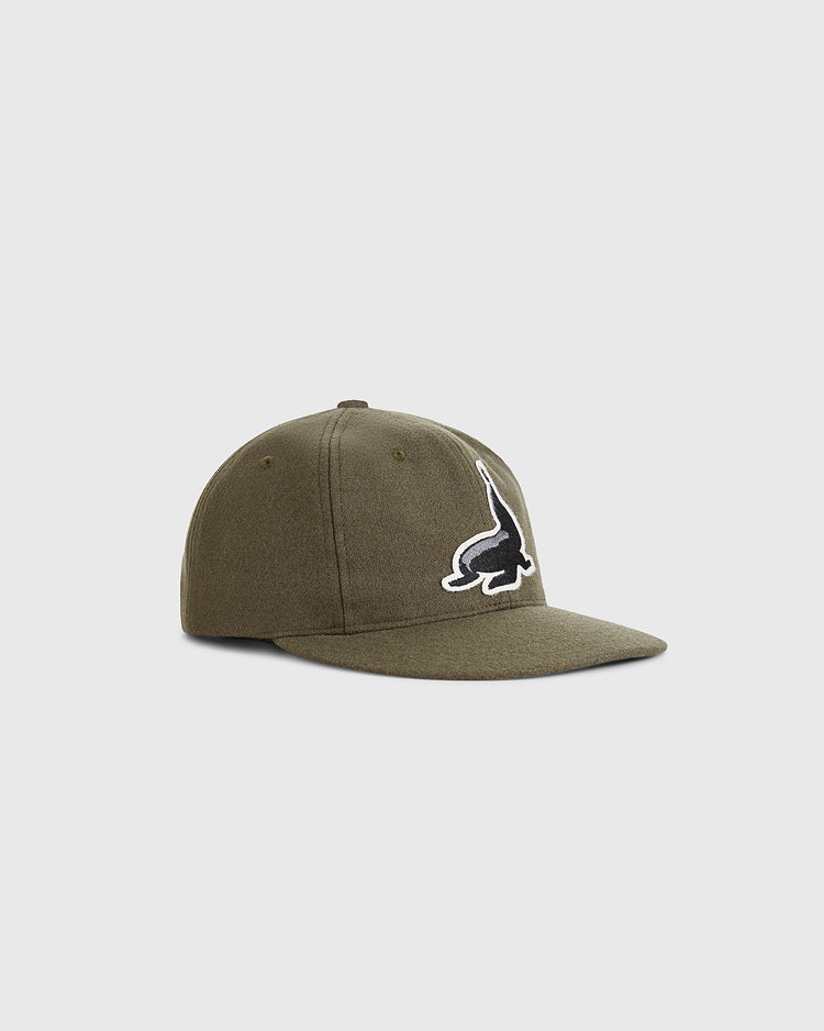The Guinness Seal Authentic Wool Ballcap by Ebbets Field, in olive green, features a black and white dinosaur logo on the front and is displayed against a plain light gray background.