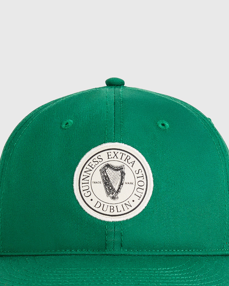 The Ebbets Field Guinness Extra Stout Badge Cotton Twill Ballcap is a green baseball cap with a front circular patch featuring a harp and 
