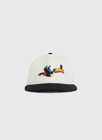 The Guinness Flying Toucan Authentic Wool Ballcap by Ebbets Field features a white crown, black brim, and an embroidered toucan with a yellow beak in flight on the front.