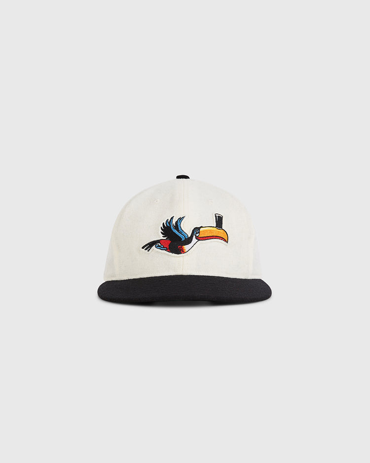 The Guinness Flying Toucan Authentic Wool Ballcap by Ebbets Field features a white crown, black brim, and an embroidered toucan with a yellow beak in flight on the front.