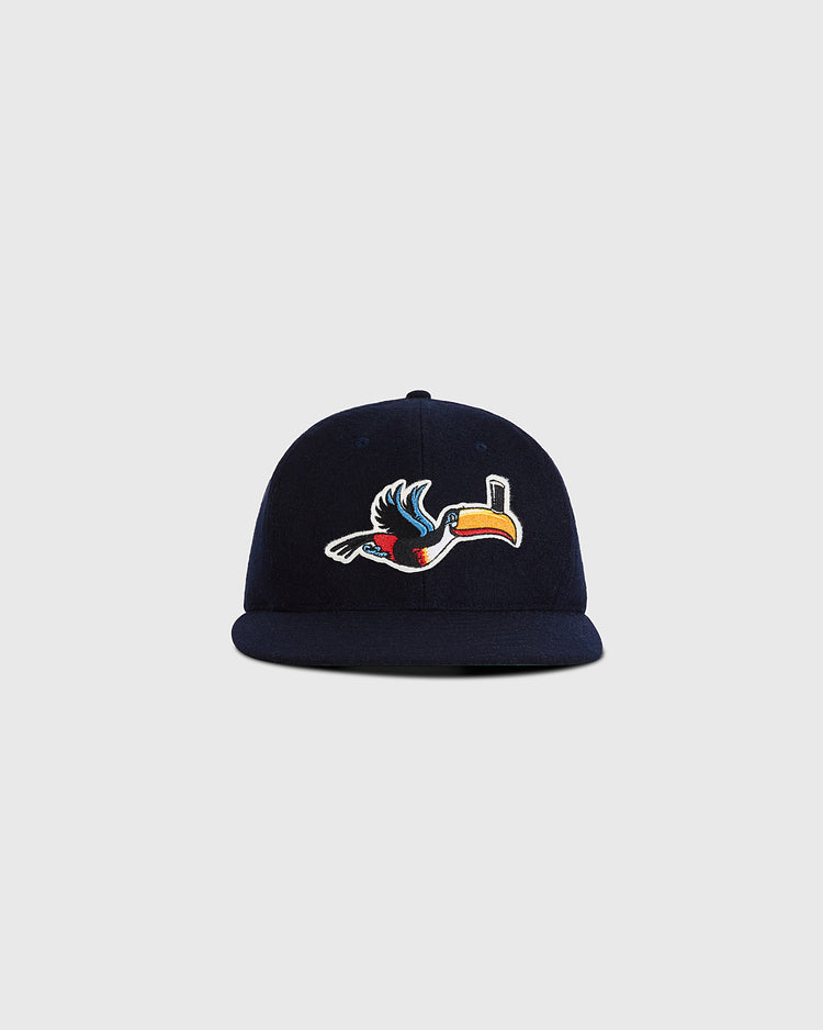 The Guinness Flying Toucan Authentic Wool Ballcap by Ebbets Field is a navy blue cap featuring a colorful embroidered toucan on the front, displayed against a plain light gray background.