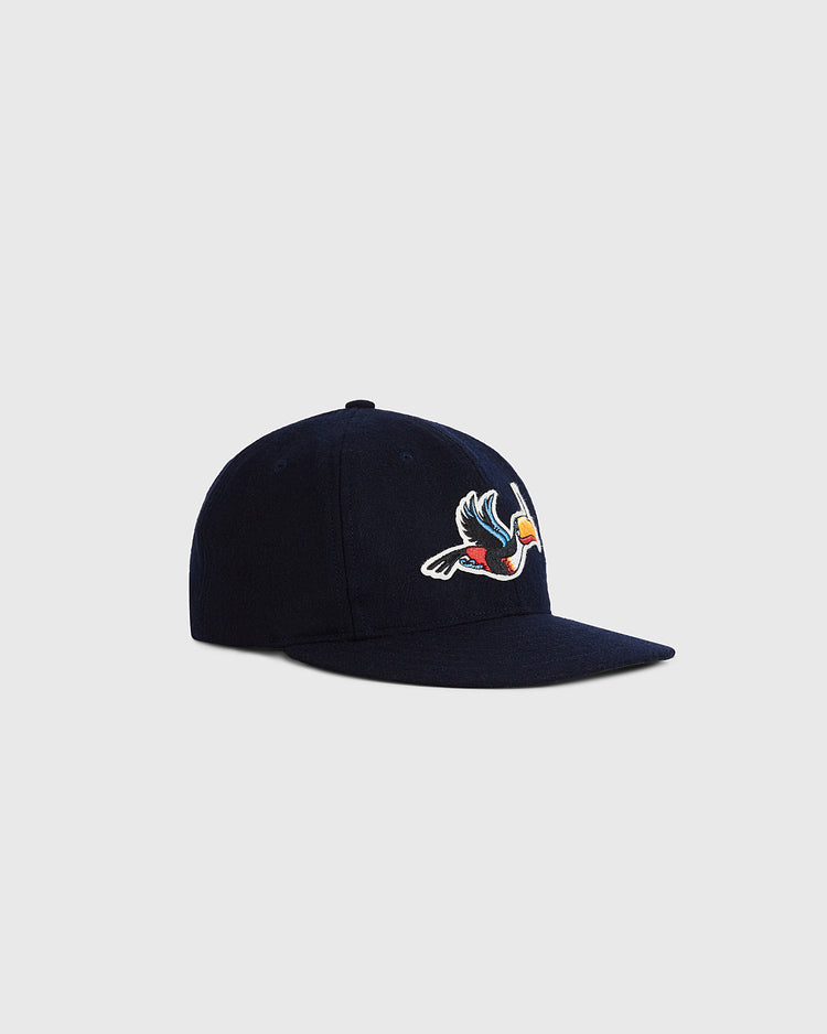 The Ebbets Field Guinness Flying Toucan Authentic Wool Ballcap is a navy blue cap with an embroidered colorful toucan in flight on the front, shown against a plain light gray background.